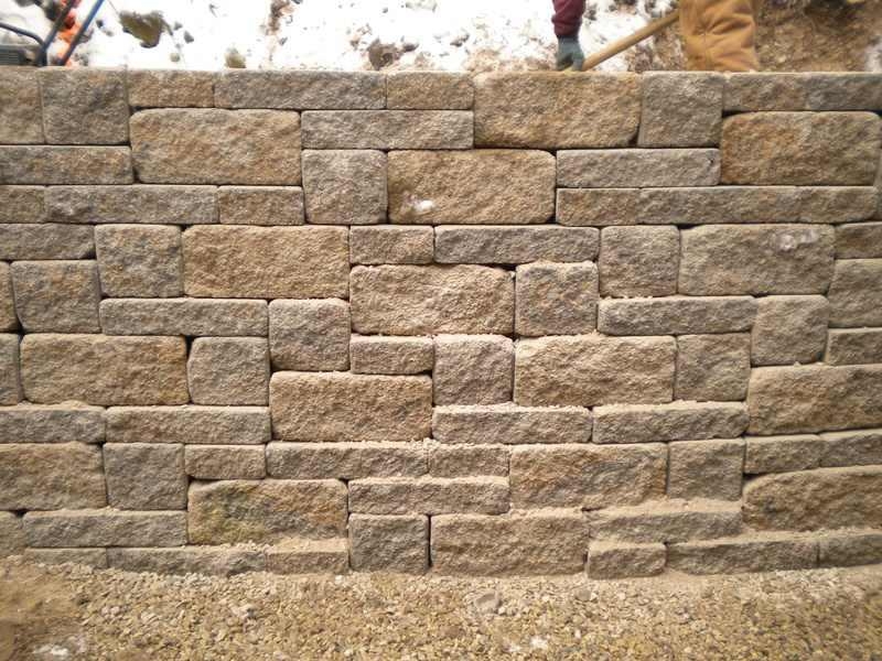 Workers install a retaining wall in the snow